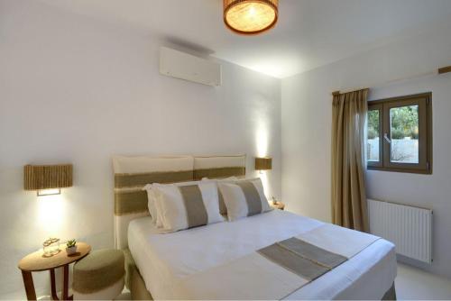 sypialnia z dużym białym łóżkiem i oknem w obiekcie Executive Paros Villa Villa Avra Sea View and Outdoor Jacuzzi Villa Kostos Damouli w mieście Paros