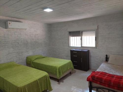 1 dormitorio con 2 camas verdes y ventana en Hermosa Casa en Jaureguiberry, en Jaureguiberry