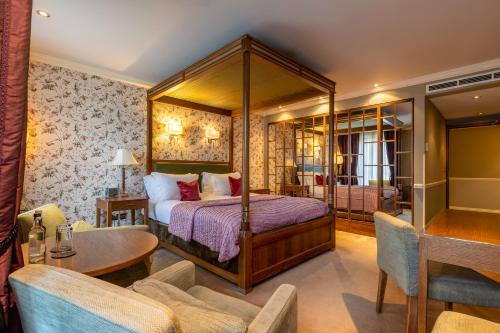 um quarto com uma cama de dossel, uma mesa e cadeiras em St Michael's Manor Hotel - St Albans em Saint Albans