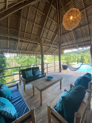 a patio with a couch and a table and hammock at Sampaguita Villas in El Nido