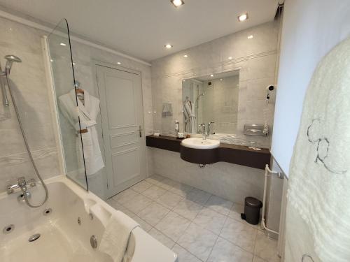 a bathroom with a tub and a sink and a shower at Hostellerie Du Chapeau Rouge in Dijon