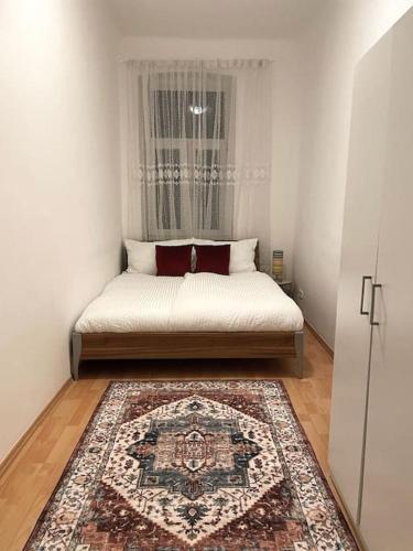 een bed in een kamer met een raam en een tapijt bij Gemütliche Wohnung in Wien in Wenen