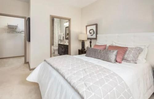 um quarto branco com uma grande cama branca com almofadas em Comfy Casa Entertainment em Charlotte