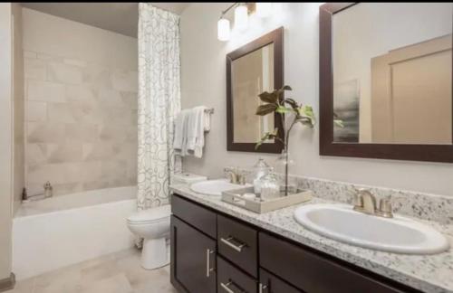 uma casa de banho com 2 lavatórios, uma banheira e um WC. em Comfy Casa Entertainment em Charlotte