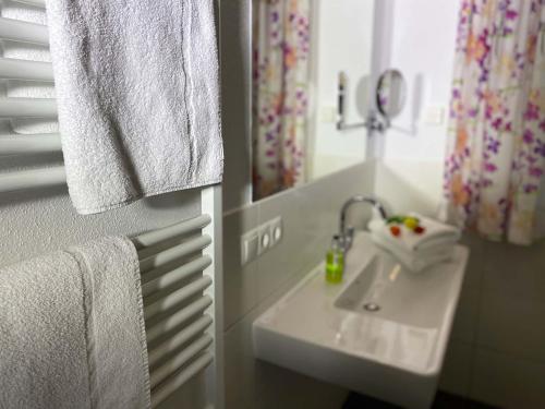 a bathroom with a sink and a mirror and towels at Art Apart Nomay Summercard Blick Top of Salzburg in Kaprun