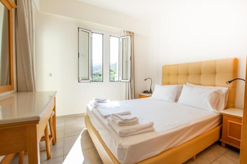 a bedroom with a bed with a desk and a window at Anastasia Hotel Stalis in Stalida