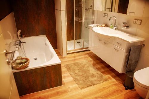 ein Bad mit einer Badewanne, einem Waschbecken und einer Dusche in der Unterkunft Ferienwohnung Saar-Steg in Saarburg