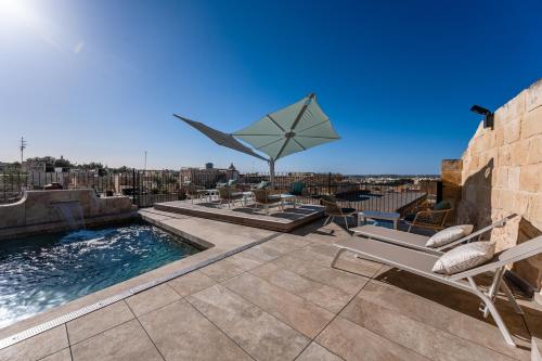 a patio with a pool and chairs and a umbrella at Palazzo Bifora in Mdina