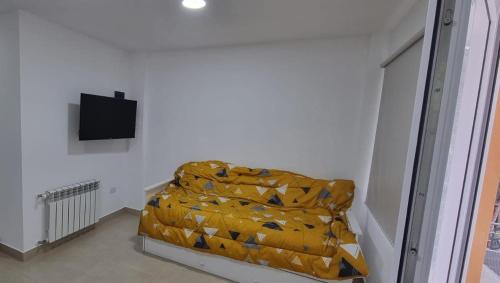Habitación con cama con manta amarilla en Los argentos en Ushuaia