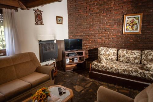 a living room with a couch and a tv at Cabañas Valle Del Sol in Tandil