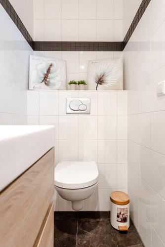 a white bathroom with a toilet and a sink at Kusthuiskatwijk in Katwijk aan Zee