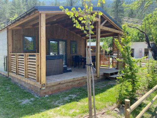 a wooden cabin with a deck in a yard at Camping La Ferme de Castellane in Castellane