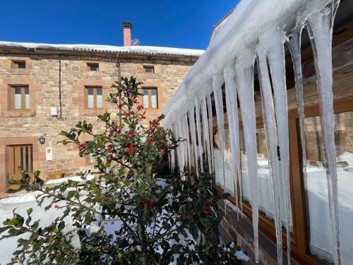 a snow covered train with a tree in front of a building at El Rincón de Golobar en Brañosera in Brañosera
