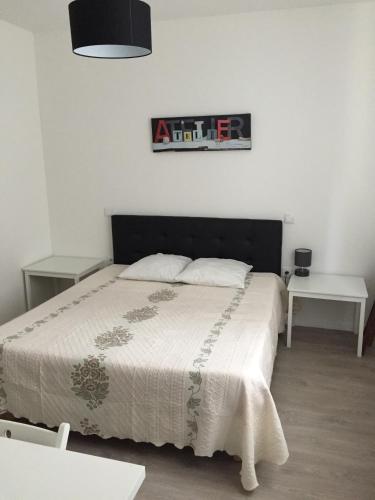 une chambre avec un lit et deux tables et une photo sur le mur dans l'établissement Hôtel Moderne, à Maisons-Alfort