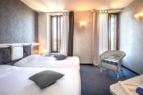 a hotel room with two beds and a chair at Logis Hôtel Restaurant Gilles Moreau Laguiole in Laguiole