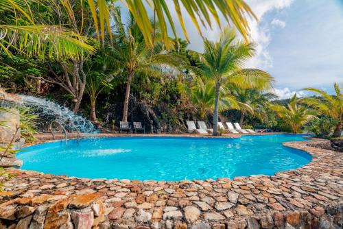 a swimming pool with palm trees and a fountain at Marina del Sol Resort & Yacht Club in Busuanga