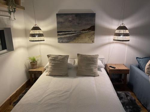 a bedroom with a white bed with two pillows at Sunnyside at Scurlage Farm in Swansea