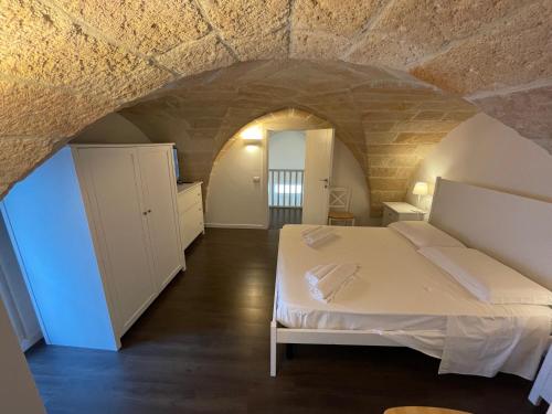 a bedroom with a white bed in a stone wall at La Casa di Rocco e Maria 1947 in Porto Cesareo
