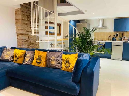 un sofá azul con almohadas amarillas en la sala de estar. en The Cider House Holiday Cottage, en Welsh Newton Common
