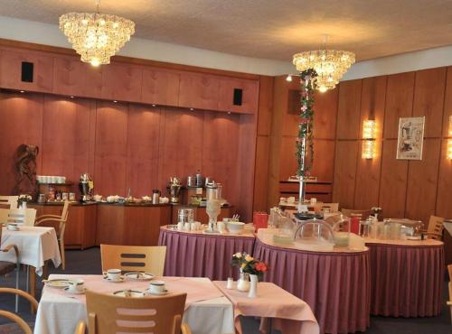 uma sala de jantar com mesas, cadeiras e lustres em Lessinghof em Braunschweig