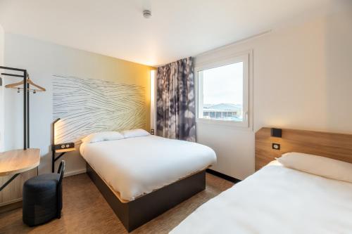 ViriatにあるB&B HOTELS Bourg-en-Bresse Viriatのベッド2台と窓が備わるホテルルームです。
