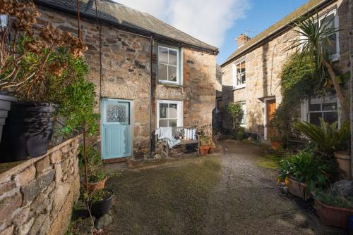 an alley in an old stone house with a blue door at Newlyn Nookery in Newlyn