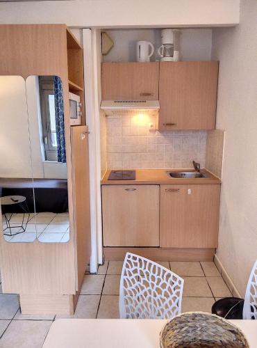 Elle comprend une petite cuisine avec des placards en bois et un évier. dans l'établissement Résidence Graziella Studio 203, à Juan-les-Pins