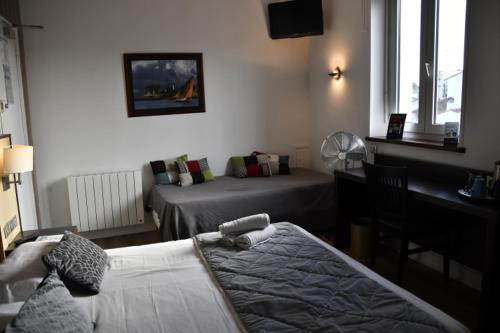 a hotel room with two beds and a desk and a desk at Hotel Le Coureau in Saint-Trojan-les-Bains