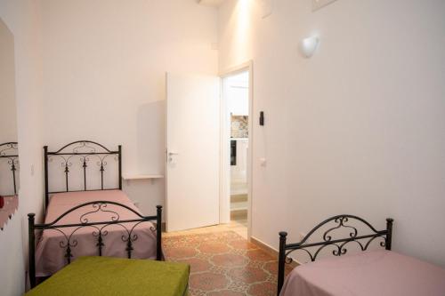 a bedroom with two beds and a door to a hallway at La Maison de La Mer in Cefalù