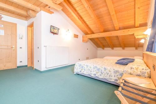 a bedroom with a bed and a wooden ceiling at Hotel Garni la Stua in Selva di Cadore