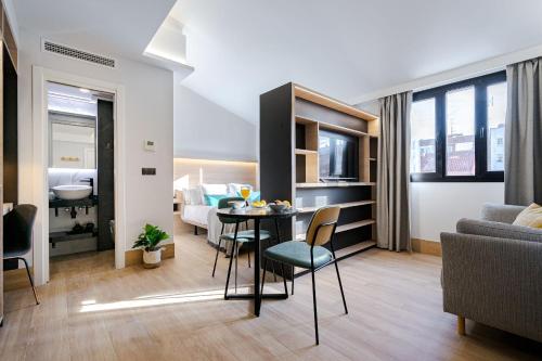 uma sala de estar com uma mesa e um sofá em Feelathome Ventas Suites em Madri