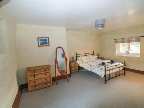 a bedroom with a bed with a mirror and a dresser at Jean's Cottage in Exeter