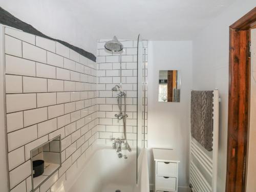 a bathroom with a bath tub with white tiles at Jean's Cottage in Exeter