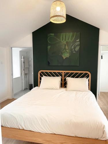 a bedroom with a large white bed with a green wall at Suite Théodore - 2 pers in Charleville-Mézières