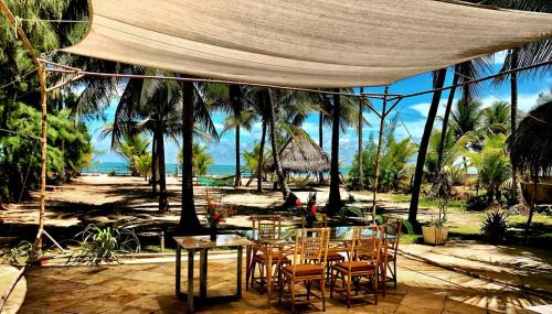 a table and chairs under a tent on a beach at Jardim Azul in Pitimbu