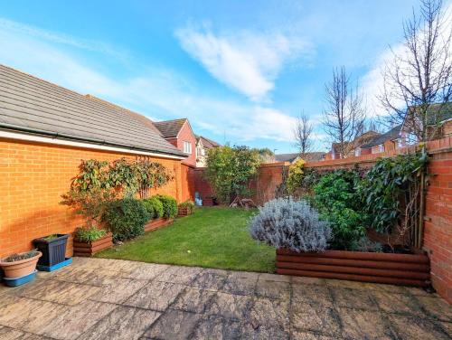 a backyard with a brick wall and a garden at Happy Days in Yapton
