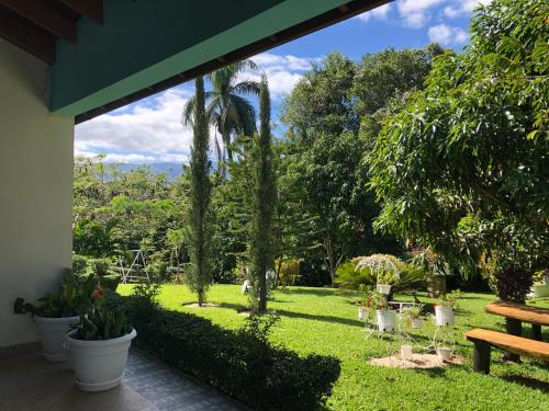 uma vista para um jardim com um banco e árvores em Rancho Jacob By Hospedify Preciosa Villa campestre con un amplio patio hermoso jardín cómodo gazebo y piscina em Jarabacoa