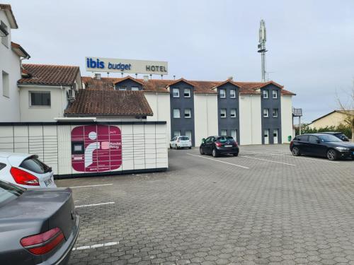 a parking lot with cars parked in front of a building at Ibis Budget Agen in Le Passage