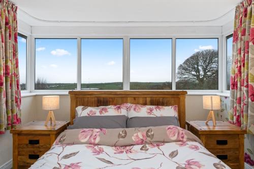 a bedroom with a bed and two windows at Comfy Cumbrian Stay in Distington