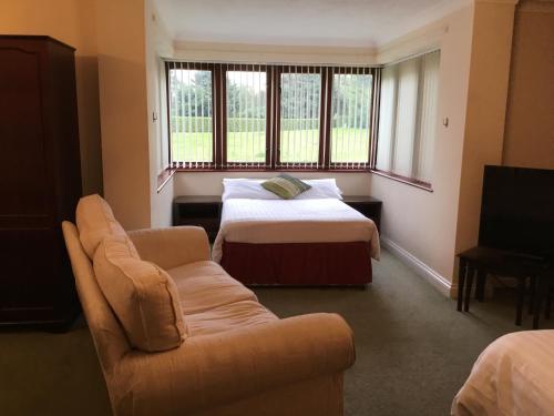 um quarto com uma cama, um sofá e uma janela em Clare House em Mundford