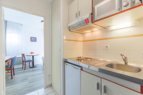 una cucina con lavandino e tavolo in una stanza di Appart'City Classic Lyon Villeurbanne a Villeurbanne