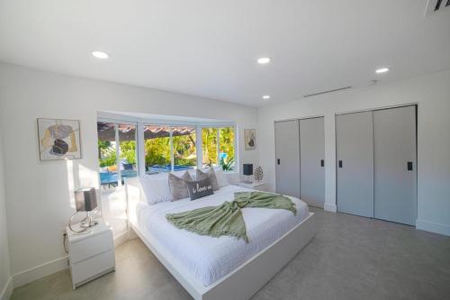 a white bedroom with a large bed and a window at Heated pool in a Precious House close to Zoo Parks and Arts in Cutler Bay