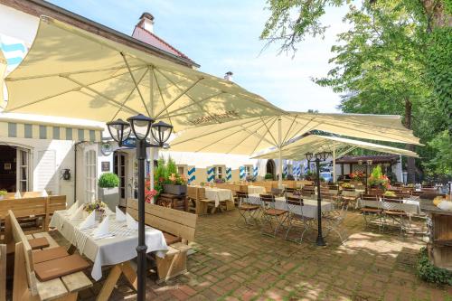 eine Terrasse mit Tischen, Stühlen und Sonnenschirmen in der Unterkunft Weichandhof in München
