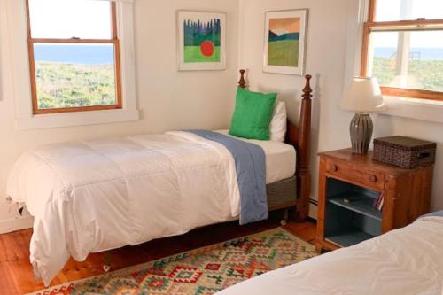 a bedroom with two beds and a table with a lamp at Valleys & Views in Nantucket