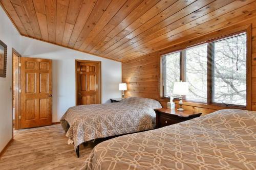 two beds in a room with wooden walls and wood floors at Bark Point Retreat in Herbster