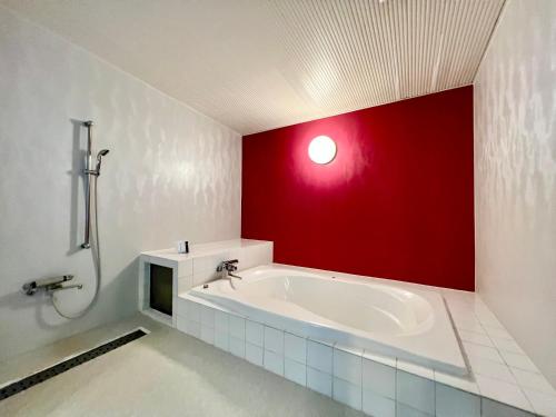 a bathroom with a bath tub with a red wall at SKY Tower Sweet 4 Beppu, Resort Love Hotel in Beppu