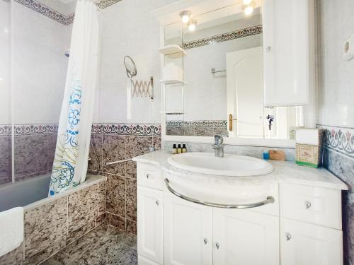 ein weißes Badezimmer mit Waschbecken und Spiegel in der Unterkunft La Manga Norte Villa - 6509 in La Manga del Mar Menor