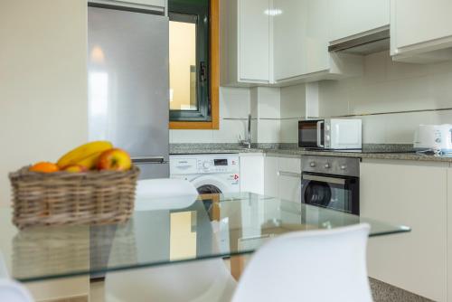 a kitchen with a basket of fruit on a glass table at Apartagal-Costa Reinante Spa in Barreiros