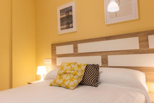 a bedroom with a white bed with yellow walls at Apartagal-Costa Reinante Spa in Barreiros