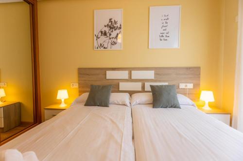 twee bedden in een slaapkamer met twee lampen en een spiegel bij Apartagal-Costa Reinante Spa in Barreiros